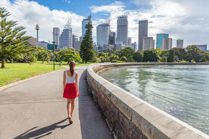 Sydney city girl tourist walking in urban park with skyscrapers skyline, Australia