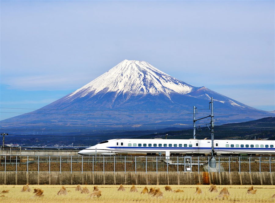 A bullet train passes below a snow-capped Mt. Fuji in Japan