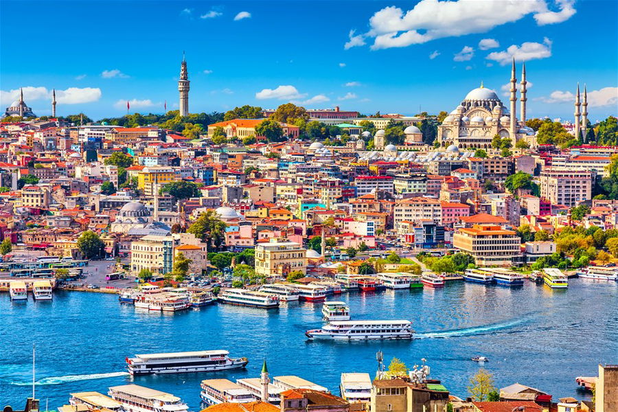 Touristic sightseeing ships in Golden Horn bay of Istanbul and mosque with Sultanahmet district against blue sky and clouds. Istanbul, Turkey during sunny summer day