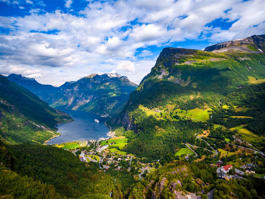 Looking down on Geiranger fjord in Norway, through green meadows, villages, onto the water below