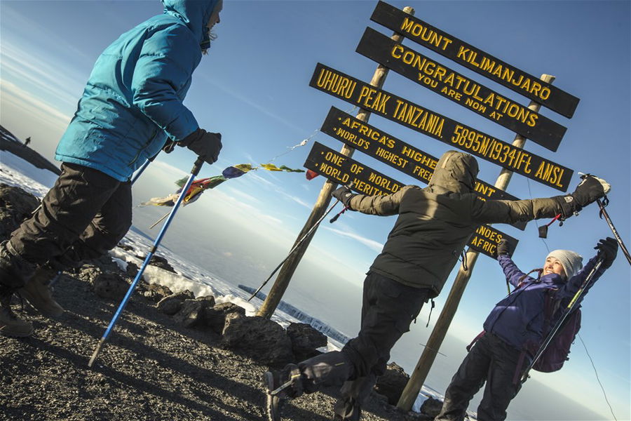 Climbers celebrating reaching the summit of Mount Kilimanjaro in Tanzania