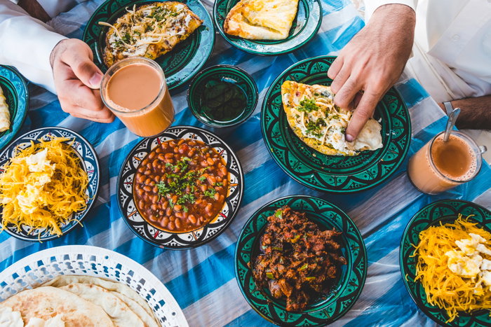 Top view of Bahraini dining table in Ramadan with Ramadan decoration, that contains Karak, samosa, Loba, Lgemat, Balalet, Eggs, and other Arab food for Breakfast and Dinner