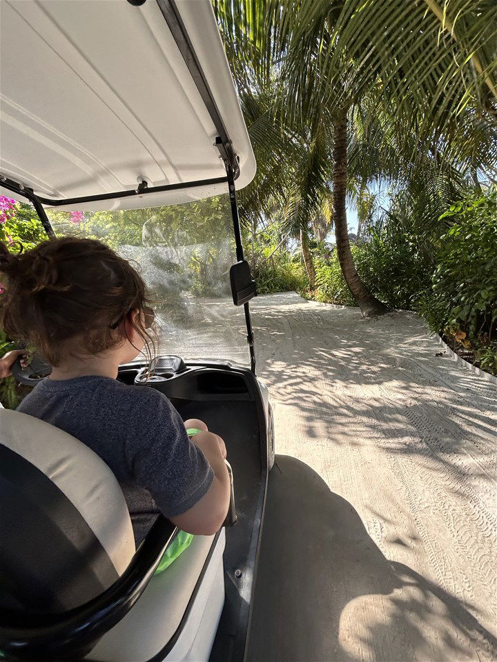 child on a golf buggy in the maldives