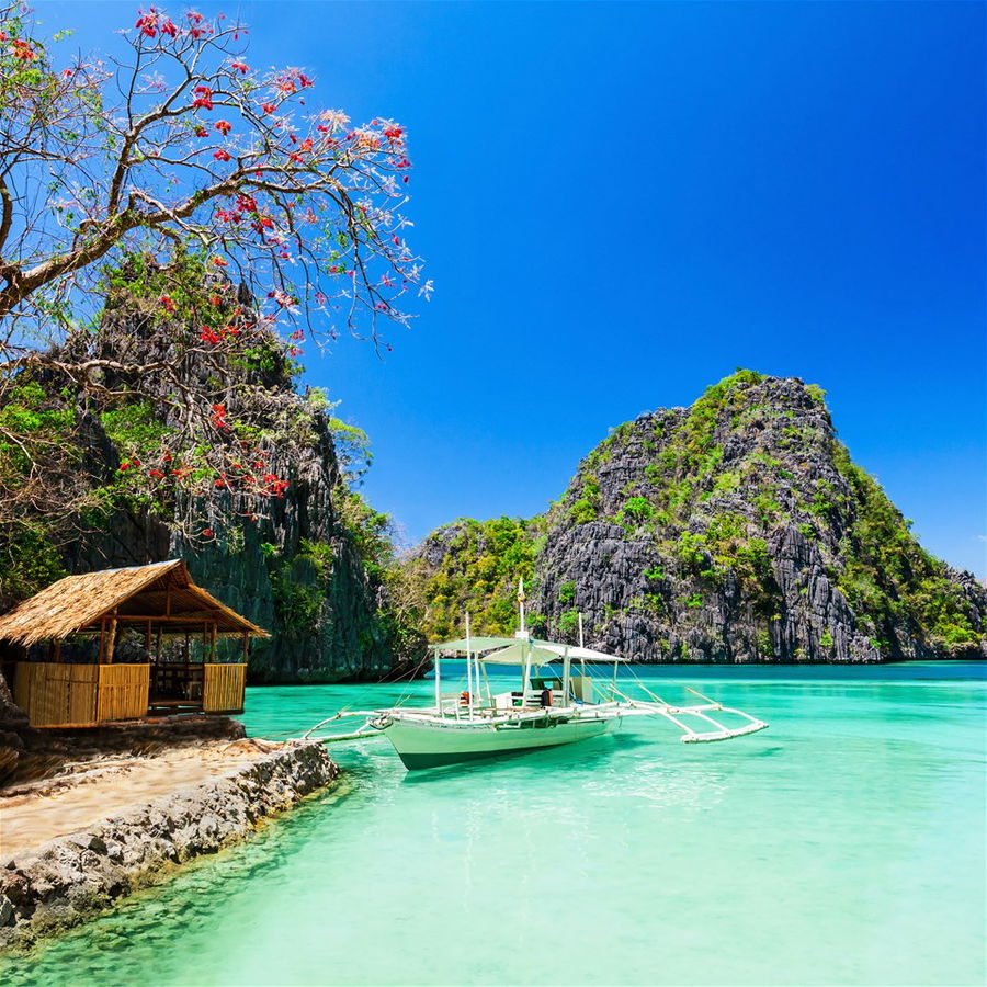 A overwater bungalow with mountains in the background in the Philippines